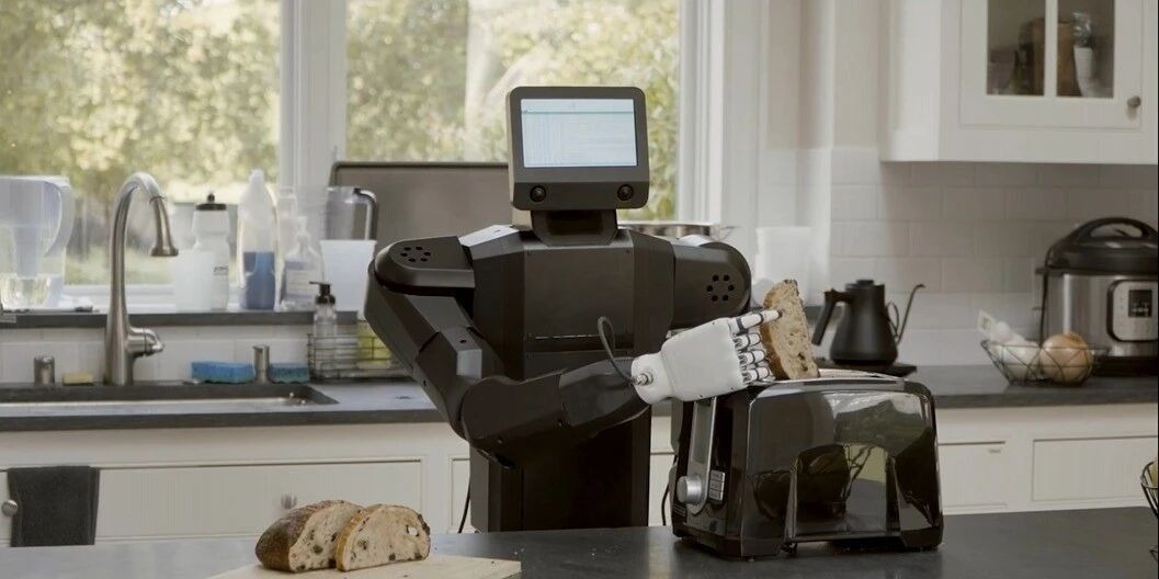 A humanoid robot operating a toaster in a kitchen setting